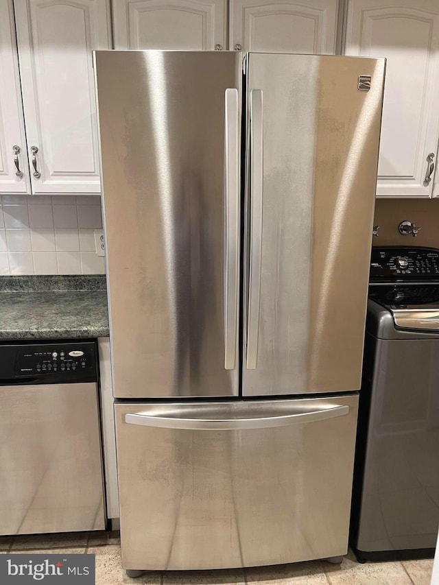16 Stonehenge Cir Unit 16-5, Pikesville, MD 21208 - kitchen with appliances with stainless steel finishes, washer / clothes dryer, dark countertops, white cabinets, and tasteful backsplash