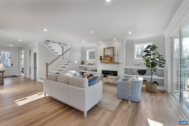 living room featuring a fireplace, light wood-type flooring, and crown molding