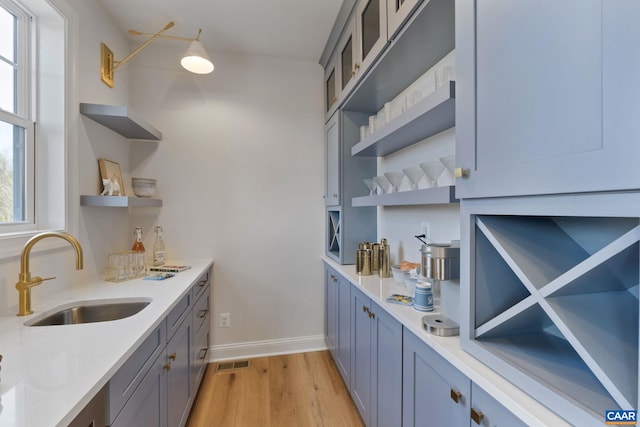 kitchen with gray cabinets, light hardwood / wood-style flooring, and sink