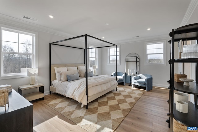 bedroom with light hardwood / wood-style floors, multiple windows, and ornamental molding