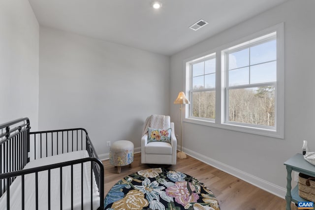 bedroom with hardwood / wood-style floors and a crib