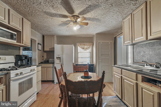 kitchen featuring light wood-type flooring, a textured ceiling, white appliances, ceiling fan, and sink