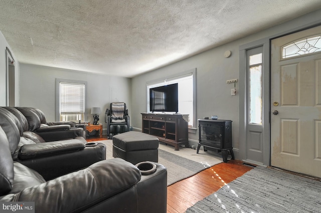 living room with hardwood / wood-style floors, a wood stove, and a textured ceiling