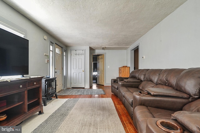 living room featuring light wood-type flooring, a textured ceiling, and a wood stove