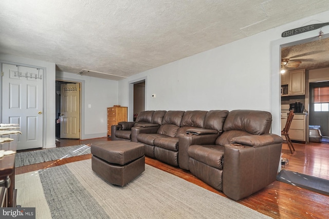 living room featuring ceiling fan, wood-type flooring, and a textured ceiling