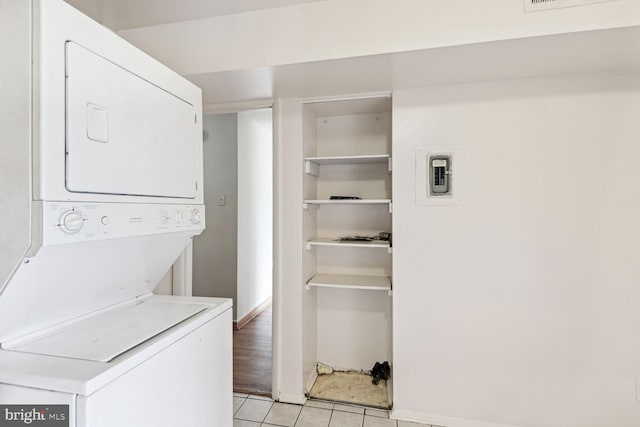 laundry room featuring light tile patterned floors and stacked washer / drying machine