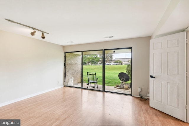 spare room featuring rail lighting and light hardwood / wood-style floors