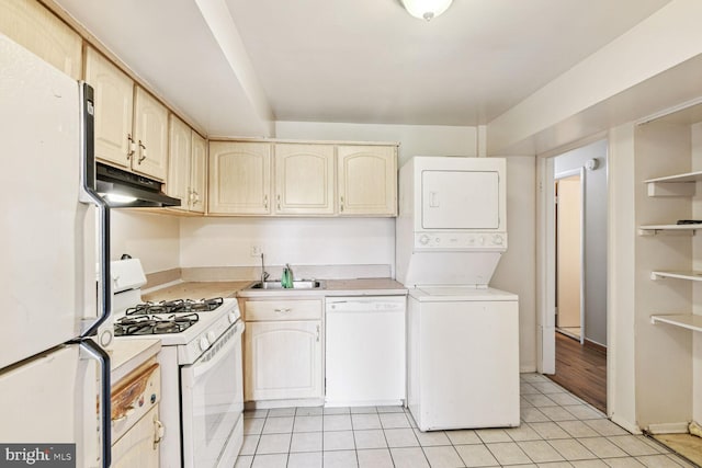 kitchen featuring light tile patterned flooring, white appliances, sink, and stacked washer and clothes dryer