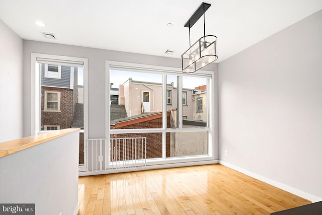 unfurnished dining area with hardwood / wood-style floors and a chandelier