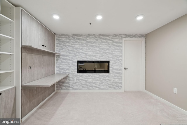 unfurnished living room with a stone fireplace and light colored carpet