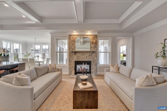 living room featuring ornamental molding, a fireplace, a healthy amount of sunlight, and coffered ceiling