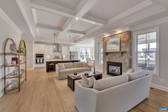 living room with light hardwood / wood-style floors, ornamental molding, beam ceiling, a fireplace, and coffered ceiling