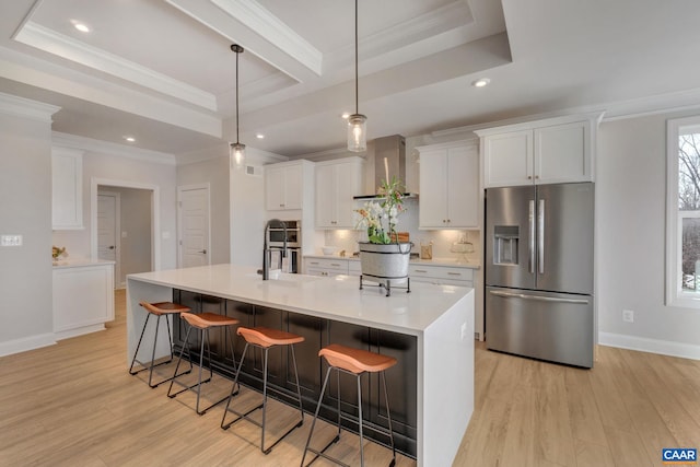 kitchen featuring pendant lighting, white cabinets, stainless steel fridge with ice dispenser, a spacious island, and light hardwood / wood-style flooring