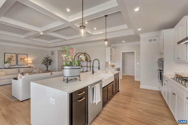 kitchen featuring a center island with sink, light wood-type flooring, appliances with stainless steel finishes, decorative light fixtures, and white cabinets