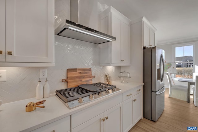 kitchen featuring white cabinetry, wall chimney range hood, light hardwood / wood-style floors, and stainless steel appliances