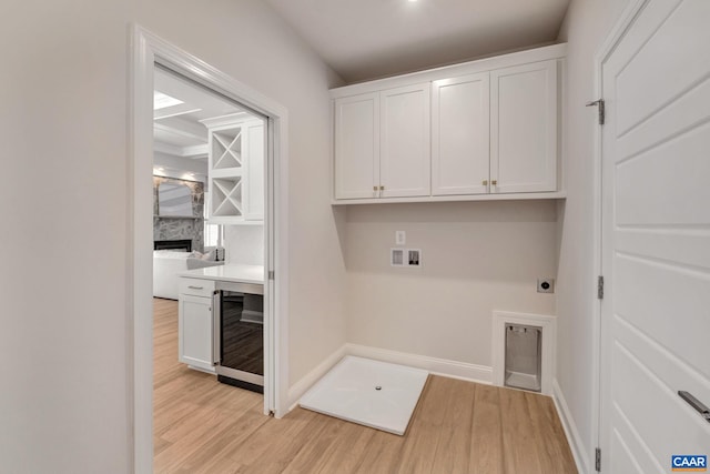 clothes washing area featuring washer hookup, light hardwood / wood-style flooring, electric dryer hookup, and wine cooler