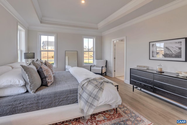 bedroom featuring ornamental molding, light hardwood / wood-style floors, and a raised ceiling