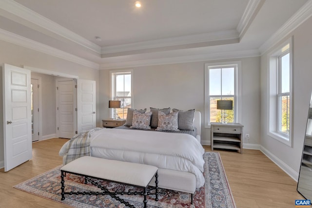 bedroom with light hardwood / wood-style floors, a raised ceiling, and crown molding