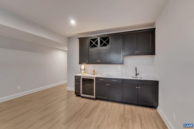 bar with light hardwood / wood-style flooring, sink, and wine cooler