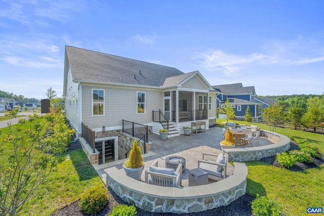 rear view of house featuring a sunroom, a yard, a fire pit, and a patio area