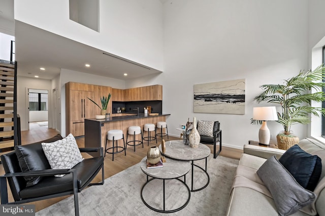 living room featuring light wood-type flooring, a wealth of natural light, and a towering ceiling