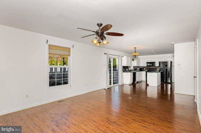 unfurnished living room featuring dark hardwood / wood-style floors and ceiling fan with notable chandelier