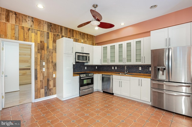 kitchen featuring ceiling fan, wood walls, sink, and appliances with stainless steel finishes