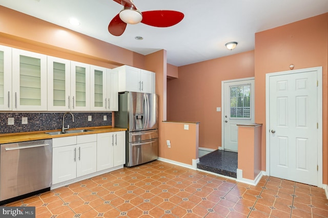 kitchen featuring appliances with stainless steel finishes, tasteful backsplash, white cabinetry, and sink