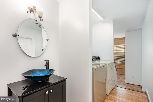 laundry area with cabinets, washing machine and dryer, light hardwood / wood-style flooring, and sink