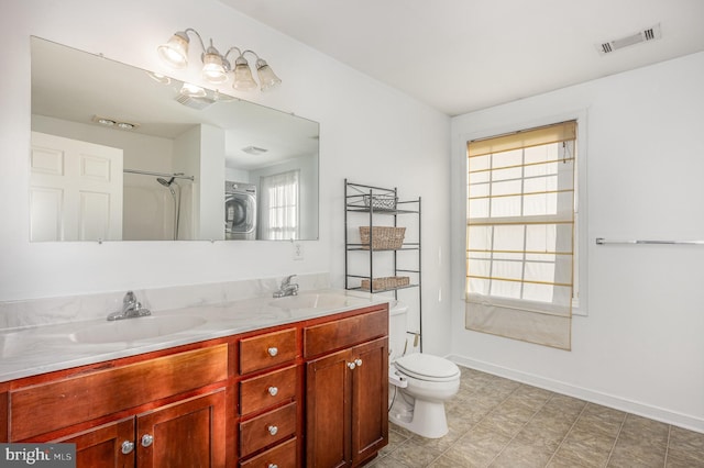 bathroom featuring vanity, stacked washer and dryer, and toilet