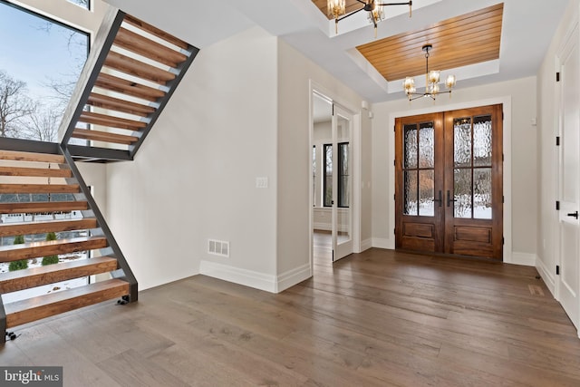 foyer entrance with a healthy amount of sunlight, french doors, a tray ceiling, and a chandelier