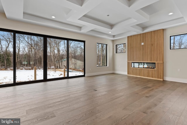 unfurnished living room with coffered ceiling, a multi sided fireplace, and hardwood / wood-style floors