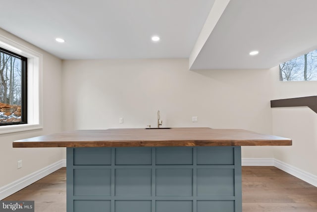 bar featuring butcher block countertops, sink, and light hardwood / wood-style floors