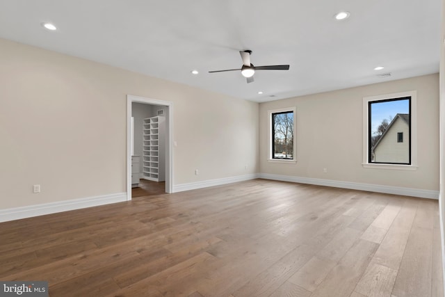 empty room with ceiling fan and light hardwood / wood-style floors