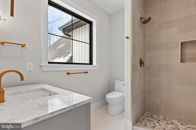 bathroom featuring toilet, vanity, and a tile shower