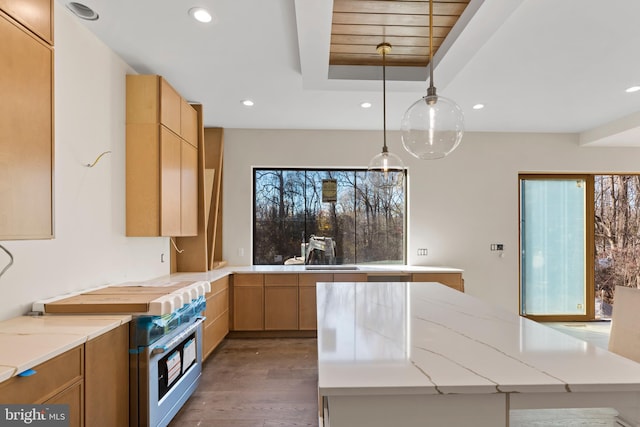 kitchen with pendant lighting, light brown cabinets, light stone counters, and high end stove