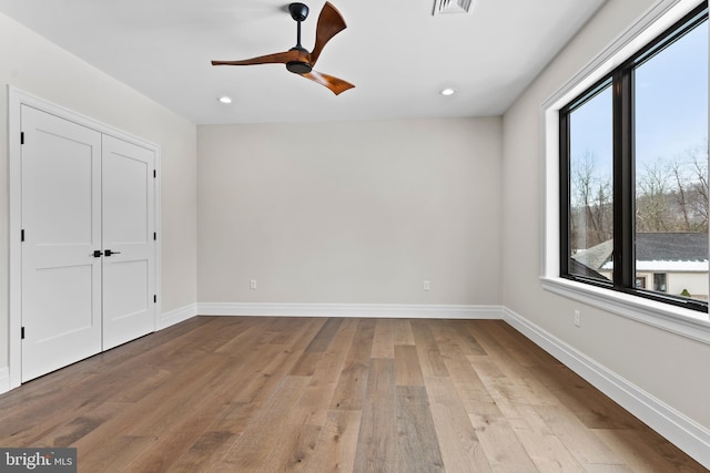 unfurnished bedroom with ceiling fan, multiple windows, and light hardwood / wood-style flooring