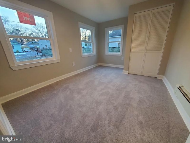 unfurnished bedroom featuring a closet, light colored carpet, and a baseboard radiator