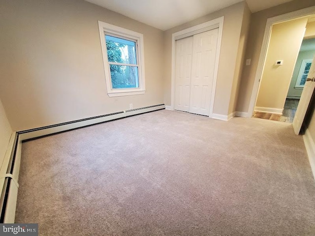 unfurnished bedroom featuring a closet, carpet, and a baseboard heating unit