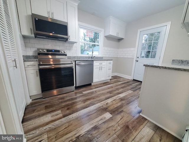 kitchen with backsplash, white cabinets, light stone countertops, dark hardwood / wood-style flooring, and stainless steel appliances