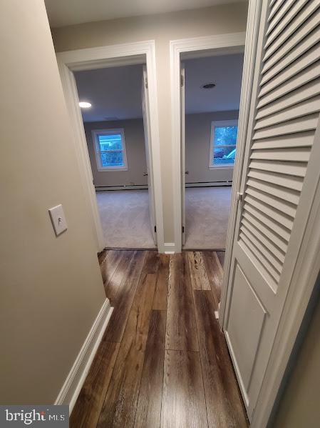 hallway with dark hardwood / wood-style flooring and a baseboard heating unit