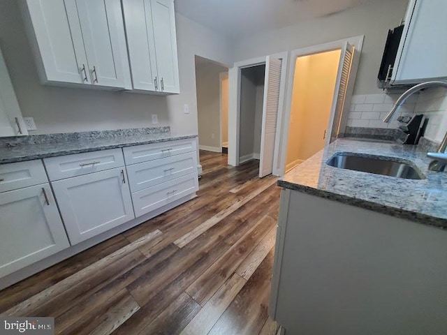 kitchen featuring decorative backsplash, light stone counters, sink, and white cabinets