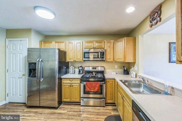 kitchen with appliances with stainless steel finishes, light wood-type flooring, light brown cabinets, and sink