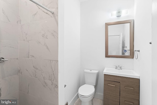 bathroom with a tile shower, vanity, and toilet