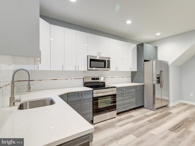 kitchen featuring light hardwood / wood-style flooring, appliances with stainless steel finishes, sink, and white cabinets