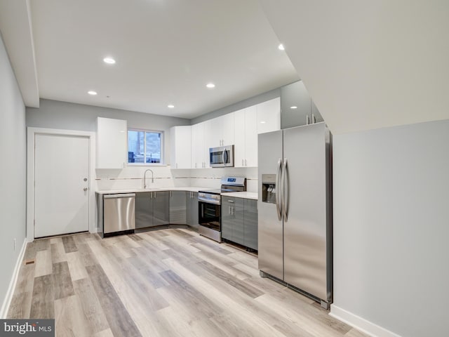 kitchen with white cabinetry, light wood-type flooring, stainless steel appliances, and sink