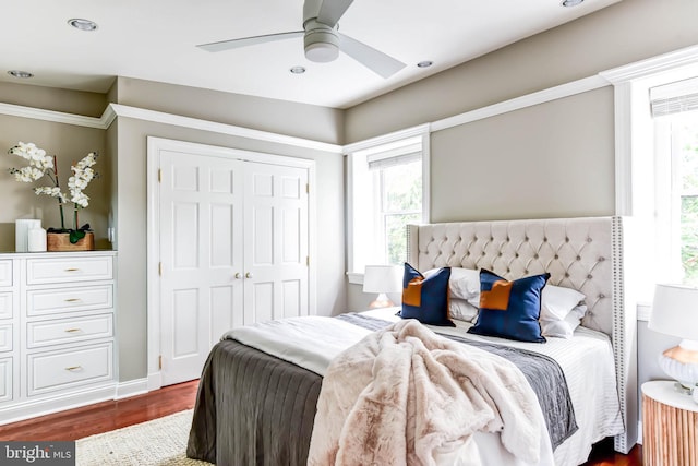 bedroom with dark hardwood / wood-style flooring, ceiling fan, and a closet