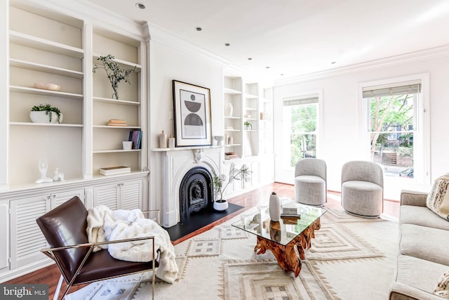 living room with built in shelves, hardwood / wood-style floors, and crown molding