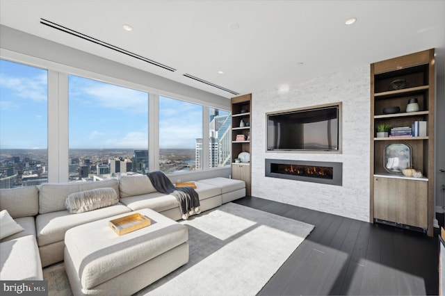 living room featuring built in shelves, hardwood / wood-style flooring, and a large fireplace