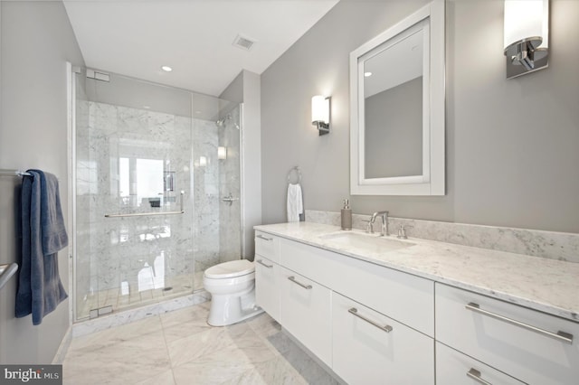 bathroom with toilet, vanity, and a shower with door